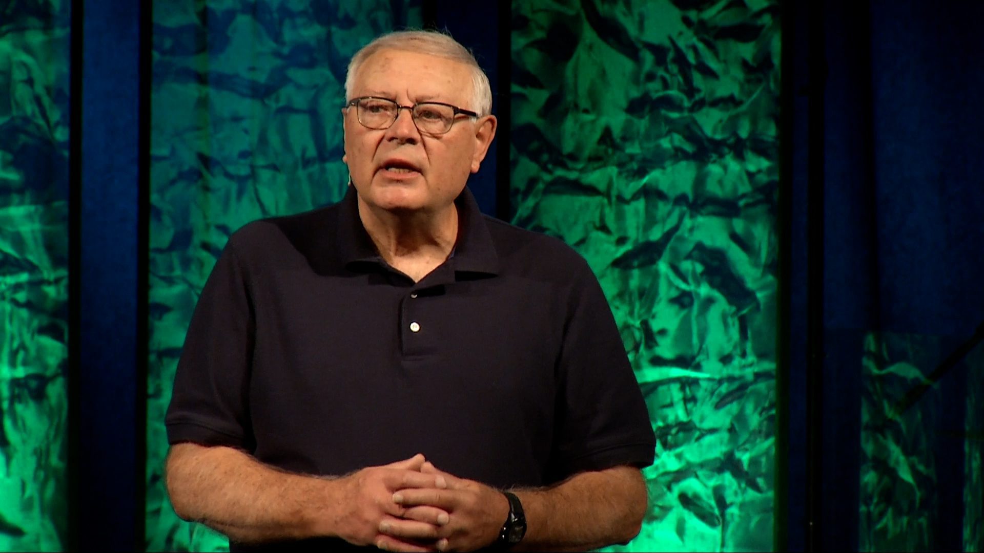 Man preaching with green lights behind him.